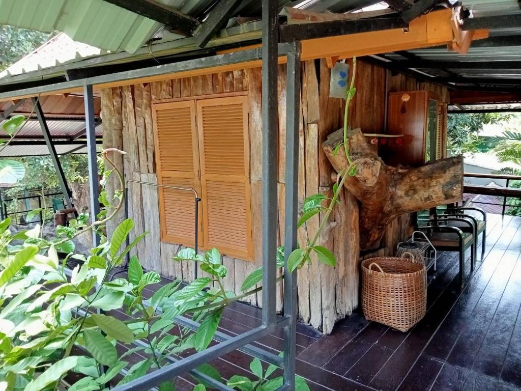 Cabaña de madera con porche con mesa y sillas en Casa Bonita Kanchanaburi en Kanchanaburi