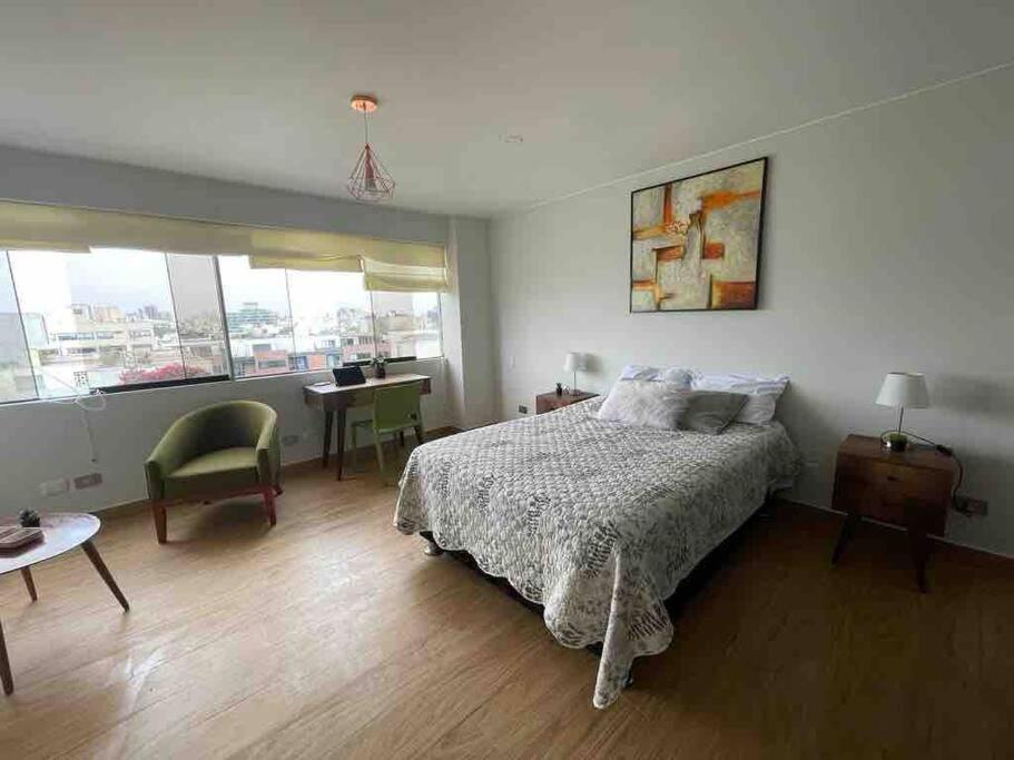 1 dormitorio con cama, mesa y escritorio en Excelente ubicación San Isidro Suite 11, en Lima