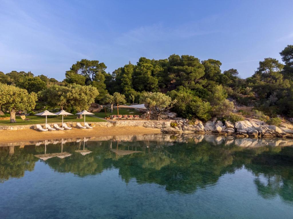 une étendue d'eau avec des chaises et des parasols sur une plage dans l'établissement The Blue Olive villa Sithonia Halkidiki, à Vourvourou