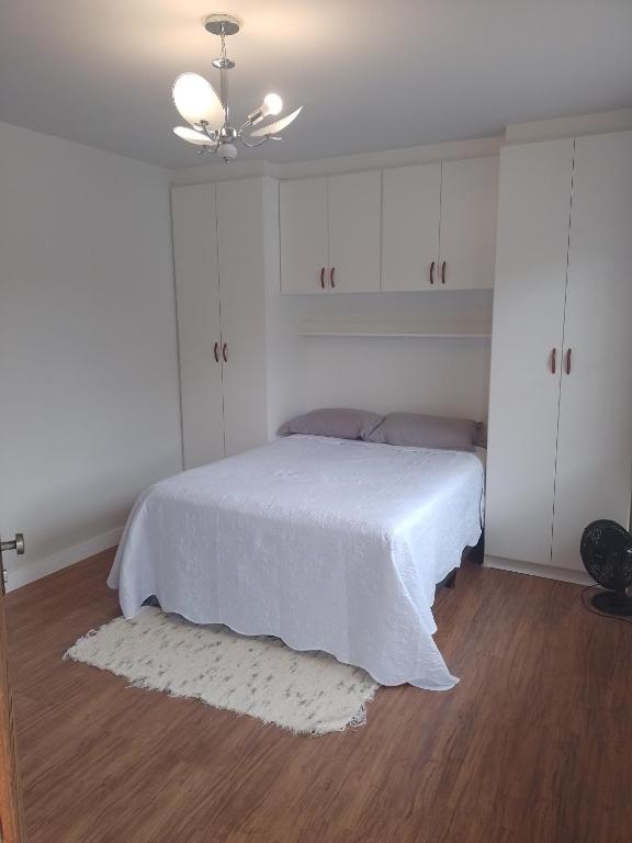 a white bedroom with a bed with a white blanket at Residencial Vitor Studio 1 in São José dos Pinhais