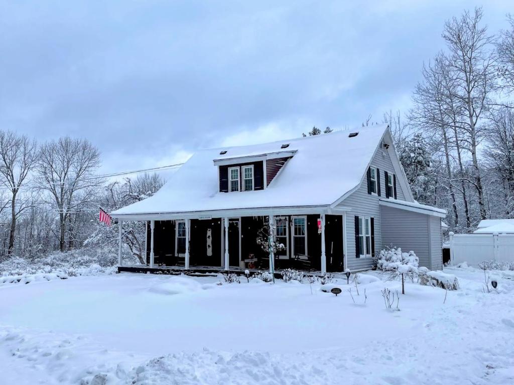 Biały dom z śniegiem na dachu w obiekcie 16LV Beautifully decorated country home 20 minutes from Bretton Woods, Cannon and Franconia Notch! w mieście Bethlehem