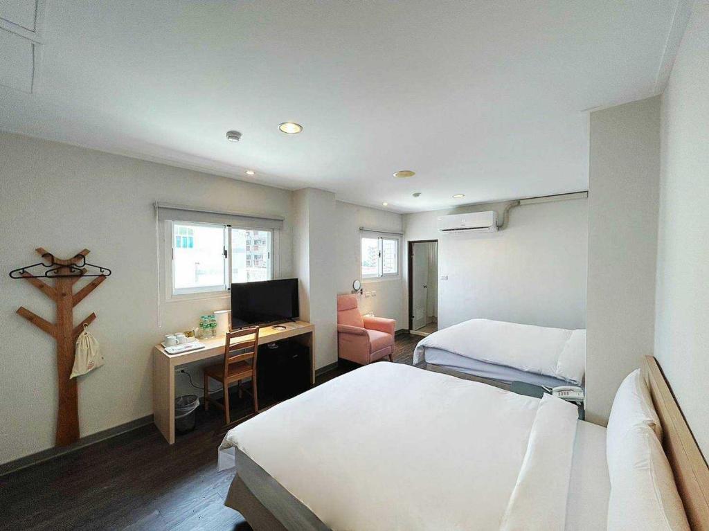 a bedroom with two beds and a desk with a television at 信然文旅-首學 寵物友善預訂前務必事先詢問 in Tainan