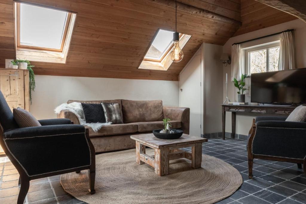 a living room with a couch and a table at Boerensuite, heerlijk verblijf in het Karschop in Riel
