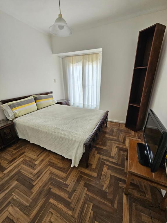 1 dormitorio con 1 cama y suelo de madera en Departamento en Plaza mitre! en Mar del Plata