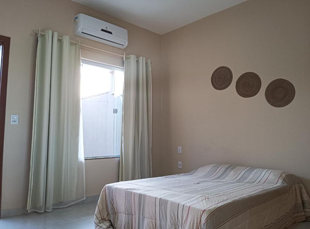 1 dormitorio con 1 cama y ventana con aire acondicionado en Casa - Luxo e Conforto, Hidromassagem a 50m do Mar, en São Mateus