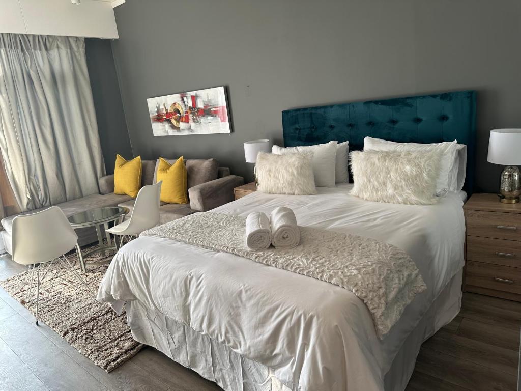um quarto com uma grande cama branca e um sofá em Menylyn Maine Residences Trilogy 913 em Pretoria