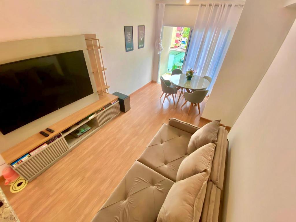 a living room with a couch and a flat screen tv at Lindo apto na Enseada - Guarujá - 8 min da praia in Guarujá