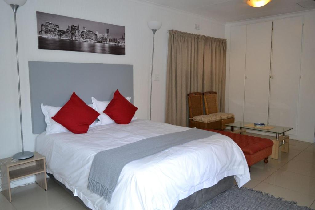 a bedroom with a large white bed with red pillows at Bryanston Elgin - Cottage 2 in Johannesburg