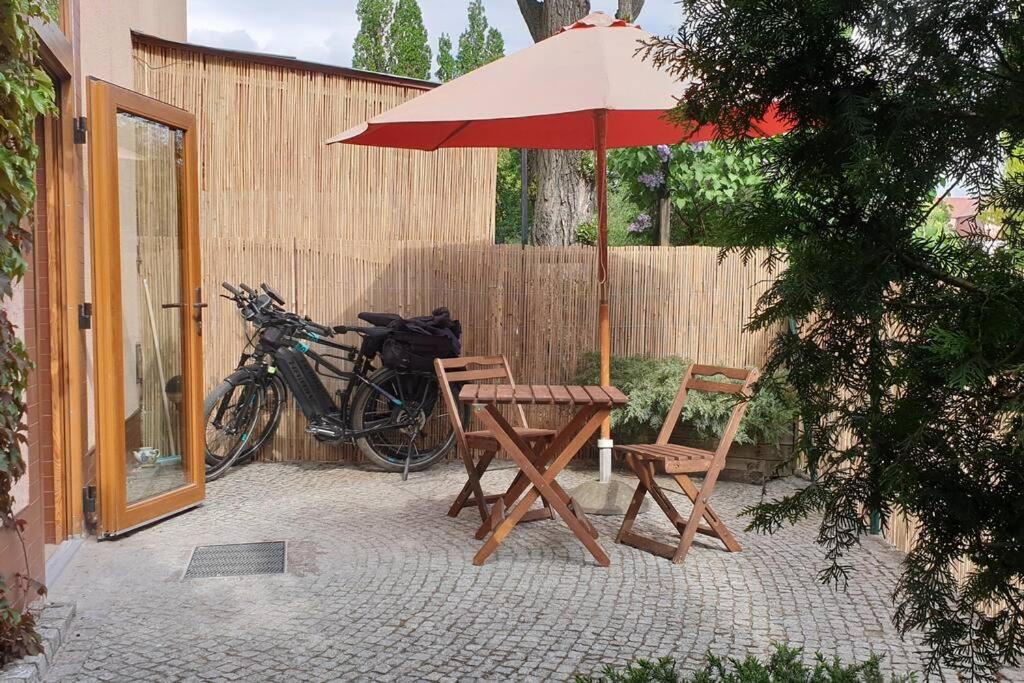 um pátio com uma mesa, cadeiras e um guarda-sol em Apartament, ogródek, przy Rynku! em Zielona Góra