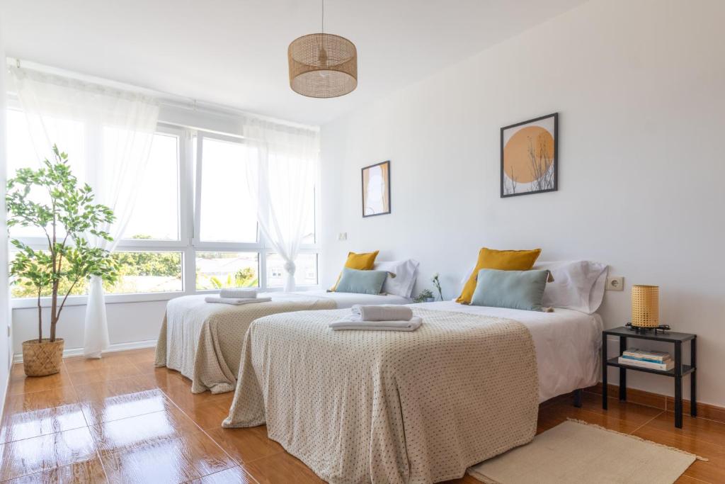 a white bedroom with two beds and a window at Senel Home in Boimorto