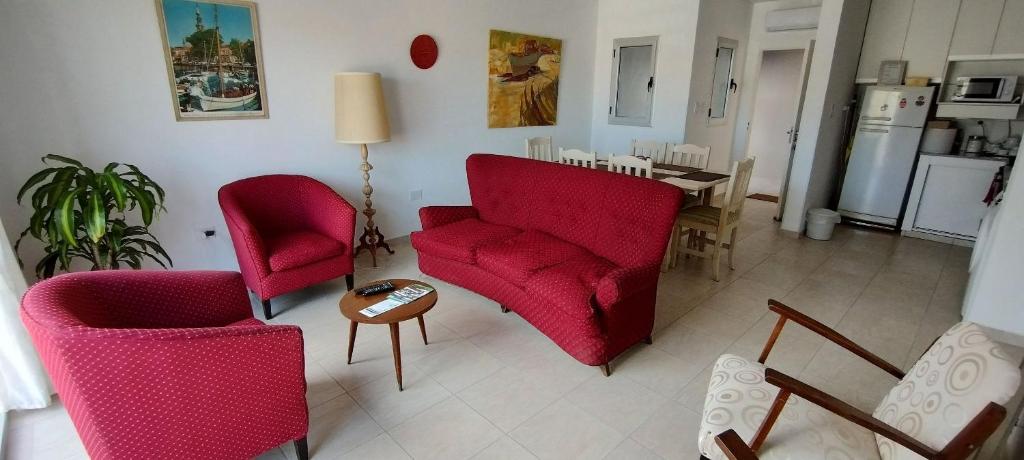 una sala de estar con 2 sillas rojas y una mesa. en Departamento ubicado en Viedma Centro. Amplio, comodo y confortable. en Viedma