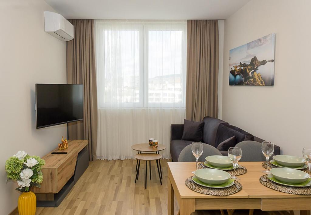 sala de estar con mesa, sofá y TV en Brand New Modern 1BD Flat In Chayka with Parking, en Varna