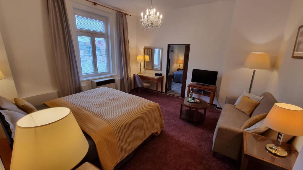um quarto de hotel com uma cama e um sofá em ContiMarienbad em Mariánské Lázně