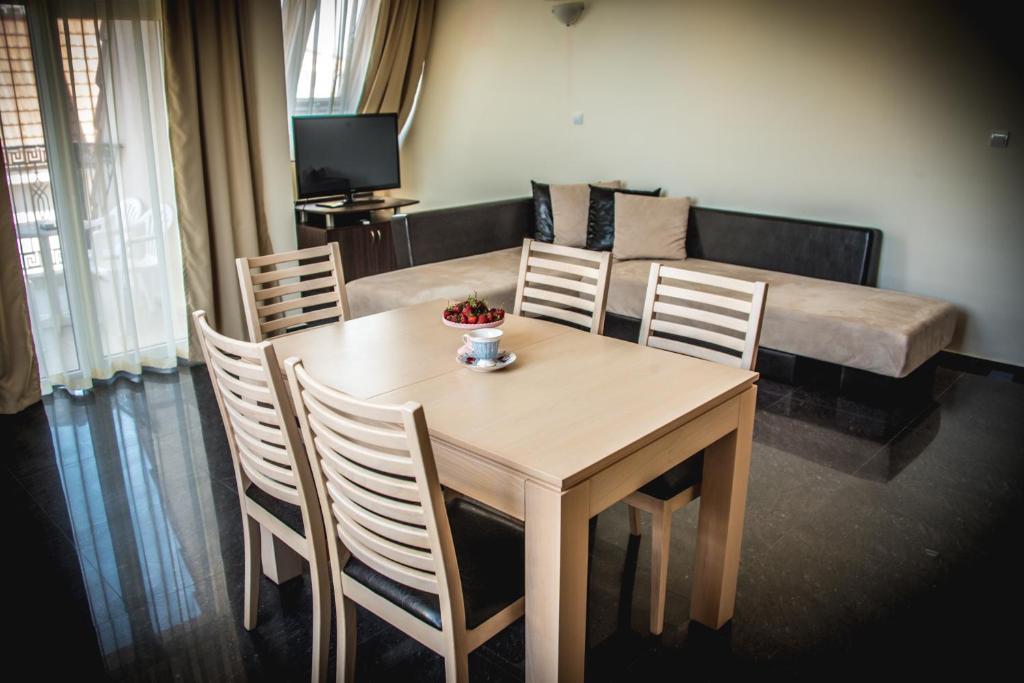 a dining room with a table and chairs and a couch at Apart Hotel Apolonia Palace in Sinemorets