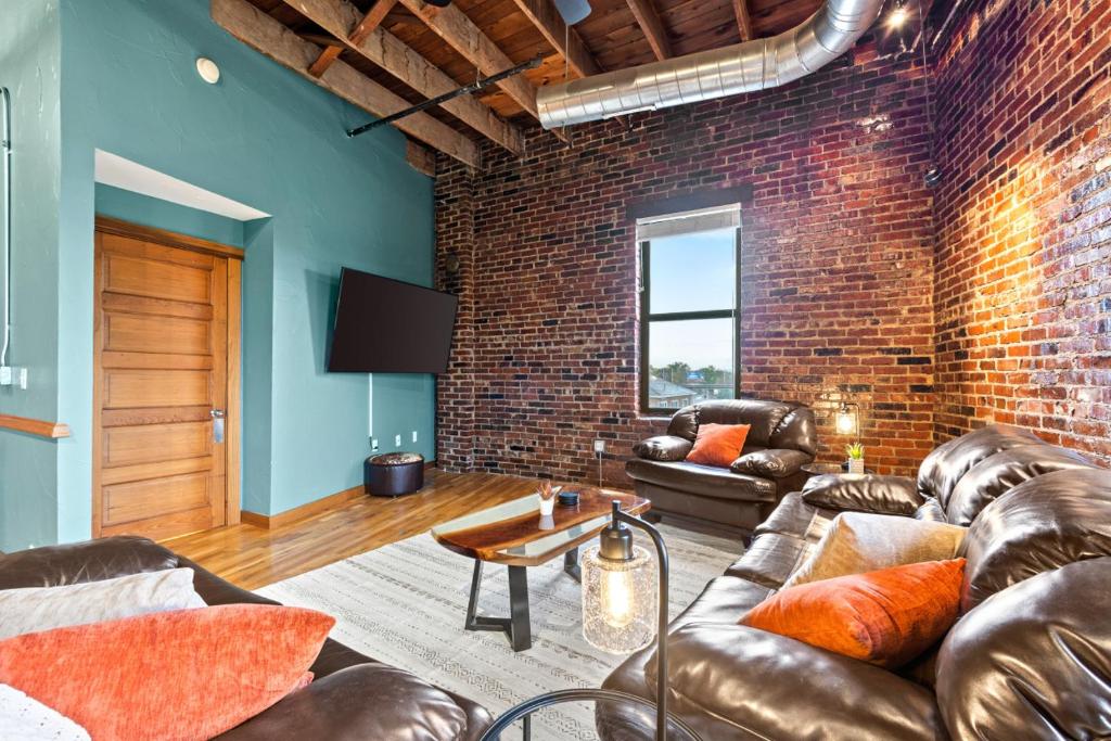uma sala de estar com mobiliário de couro e uma parede de tijolos em Railway Retreat in Downtown em Springfield