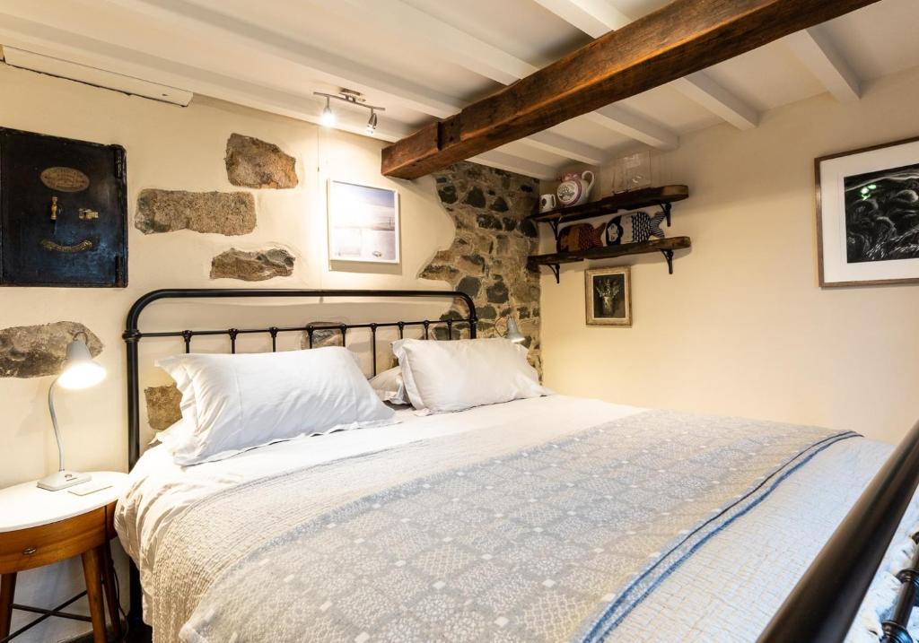 a bedroom with a bed and a stone wall at Bwthyn Capten - a charming cottage for up to 6 in Newport Pembrokeshire