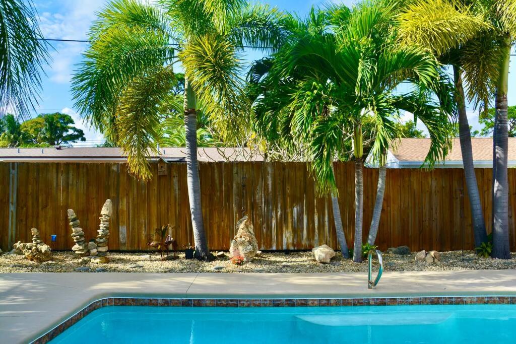 uma piscina em frente a uma cerca com palmeiras em Tropical Island Escape Near Disney, Beach, Cruise em Merritt Island