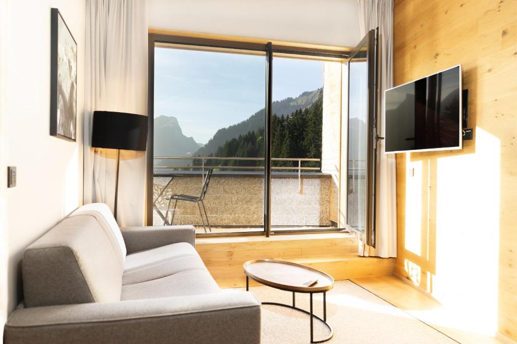 sala de estar con sofá y ventana grande en Heimat 1495m Appartement TYP 2, en Schröcken