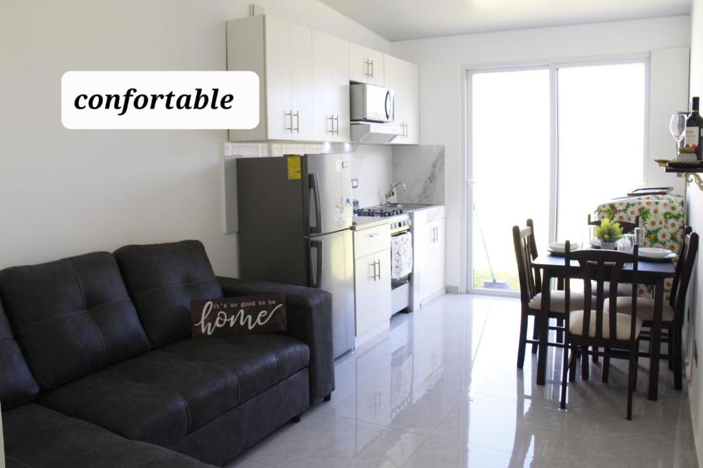 a living room with a black couch and a kitchen at Residencial Privada Nueva San miguel, casa Flores in San Miguel