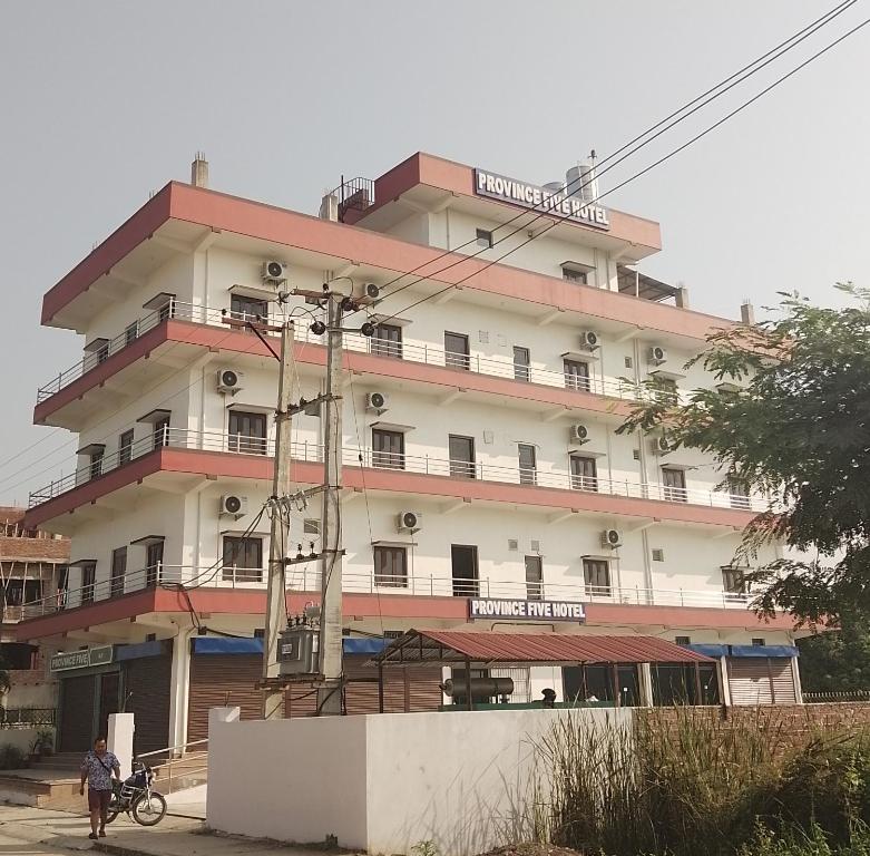 Un bâtiment avec un homme debout devant lui dans l'établissement PROVINCE FIVE HOTEL, à Siddharthanagar