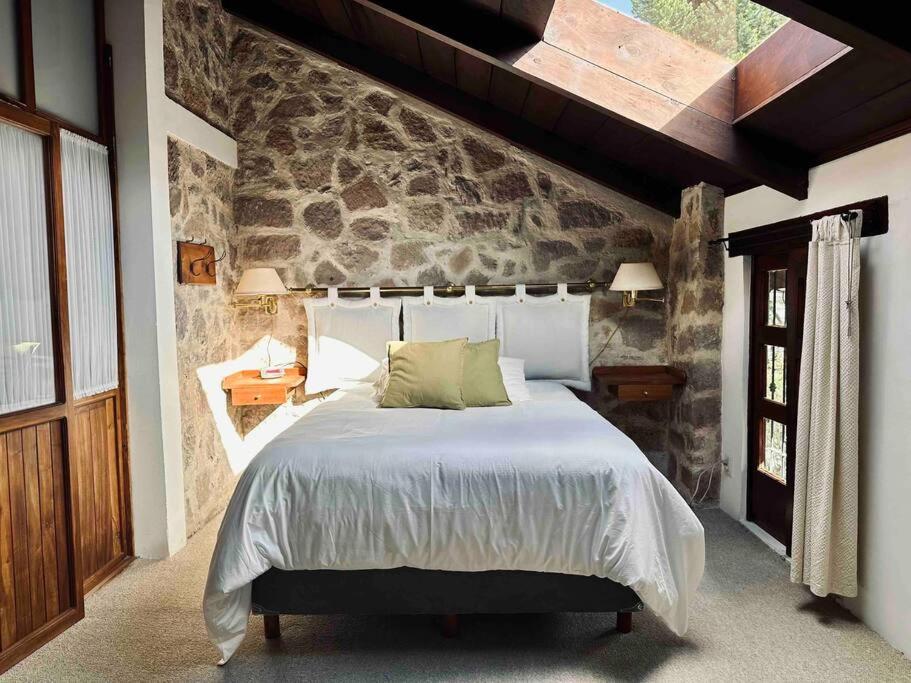 a bedroom with a large bed with a stone wall at Casa Cantera in Teziutlán