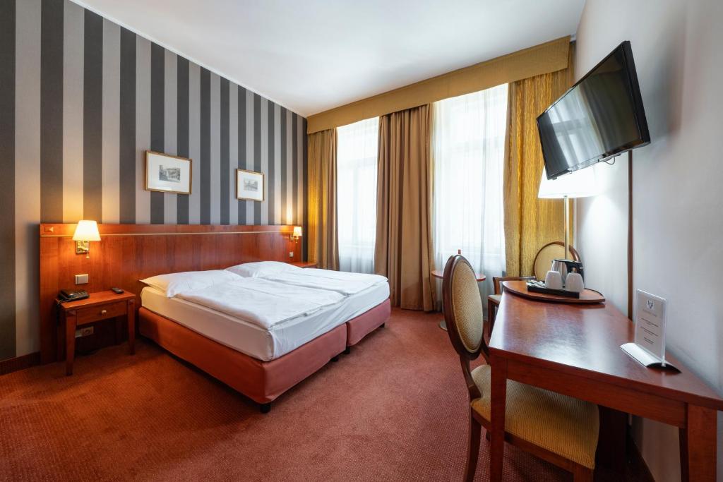 una camera d'albergo con letto, scrivania e computer di Hotel Raffaello Prague a Praga