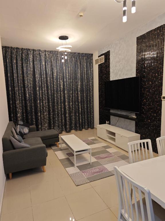 a living room with a couch and a flat screen tv at Pearl Apartment in Ajman 