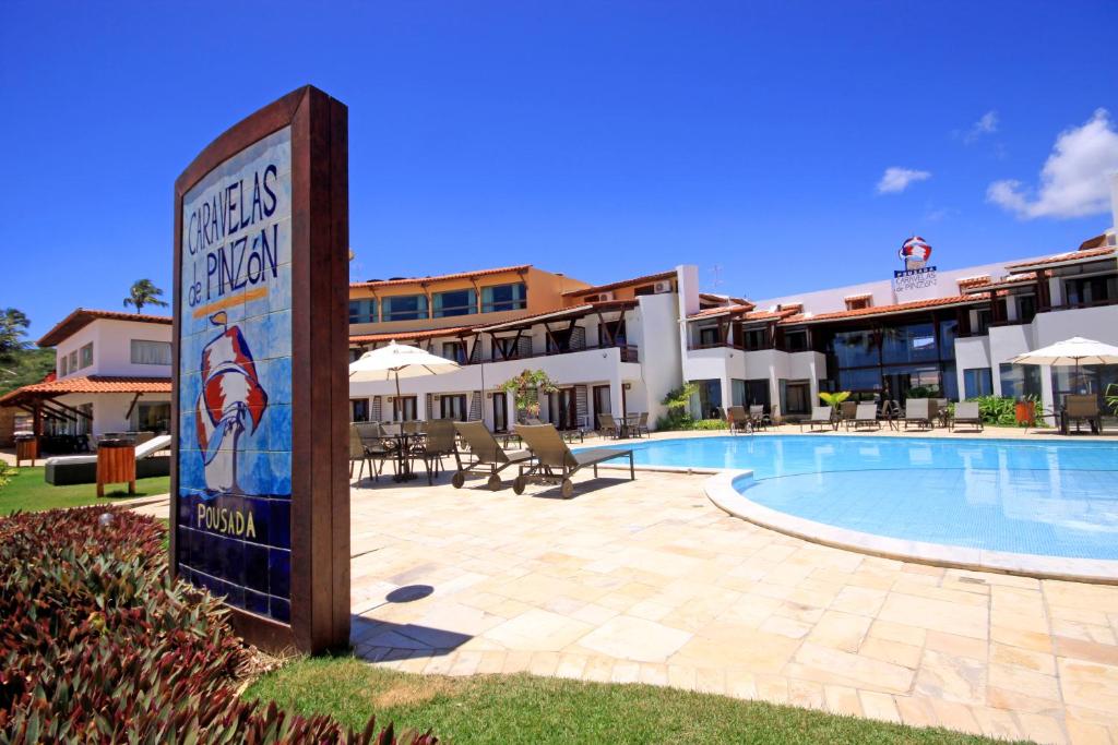 um hotel com uma placa ao lado de uma piscina em Pousada Caravelas de Pinzón em Cabo de Santo Agostinho