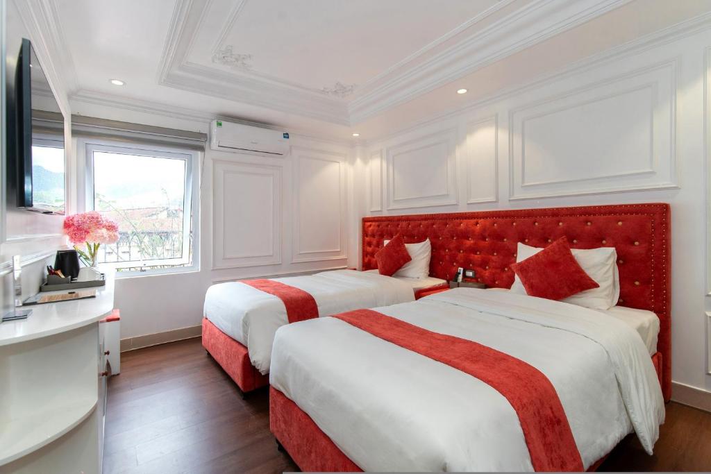 a bedroom with two beds and a red headboard at Diamond Hotel Sapa in Sa Pa