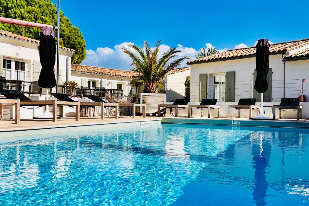 - une piscine en face d'une maison dans l'établissement Hotel Les Bois Flottais, au Bois-Plage-en-Ré