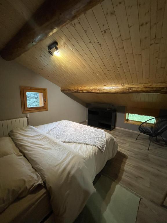 Cama en habitación con techo de madera en Appartement Chalet Petzu - 6 Pers - Parking - Ski au pied, en Levassaix