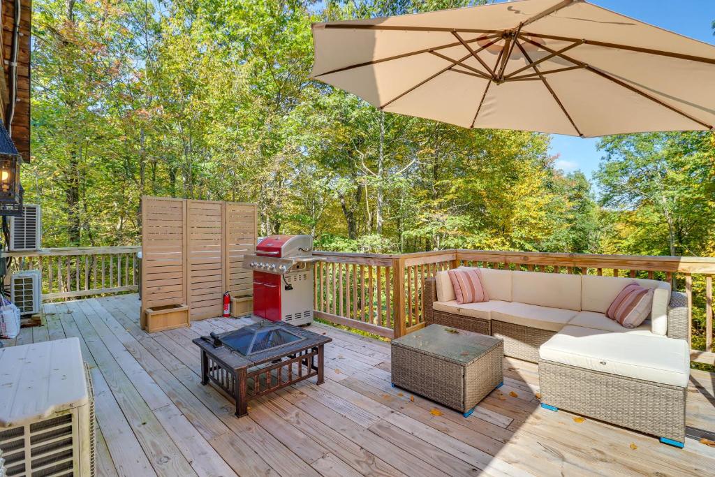 a patio with a couch and an umbrella on a deck at Private Pocono Getaway with Hot Tub and Sauna! in East Stroudsburg