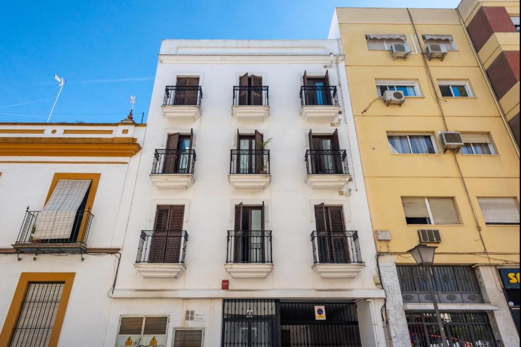 Edificio alto de color blanco con ventanas y balcones en Apartamento Moderno Con Wifi Gratis, en Sevilla