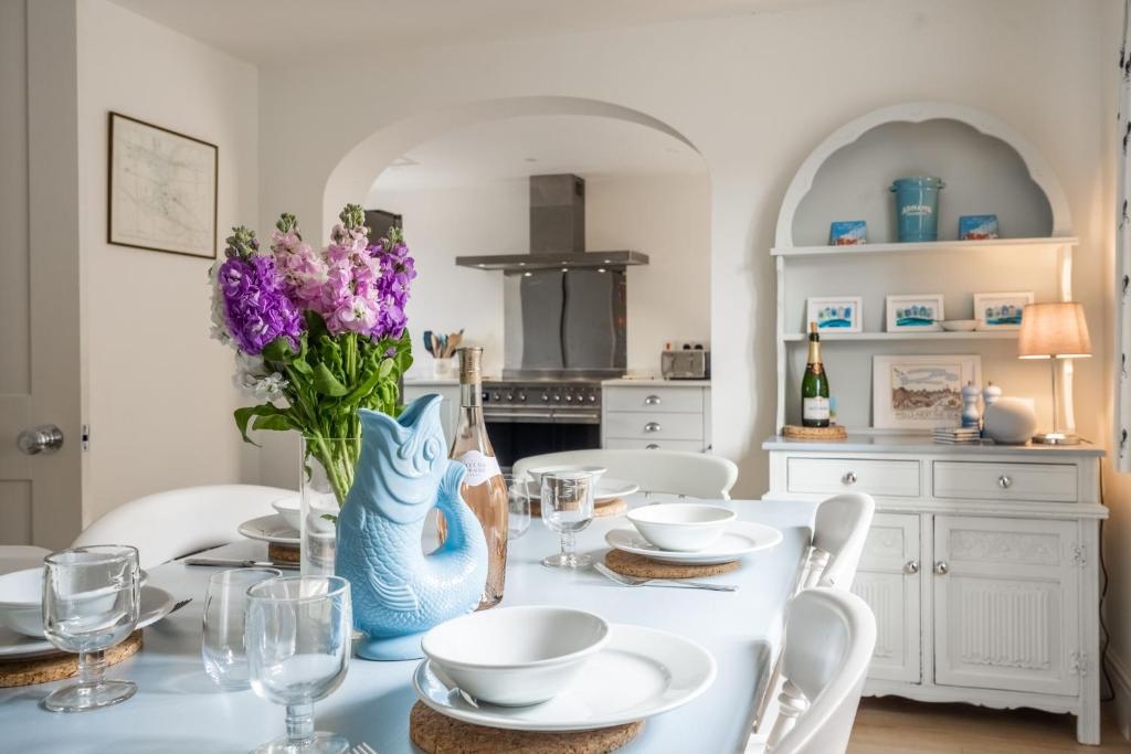 uma mesa com cadeiras brancas e um vaso azul com flores roxas em Neptune House em Wells-next-the-Sea