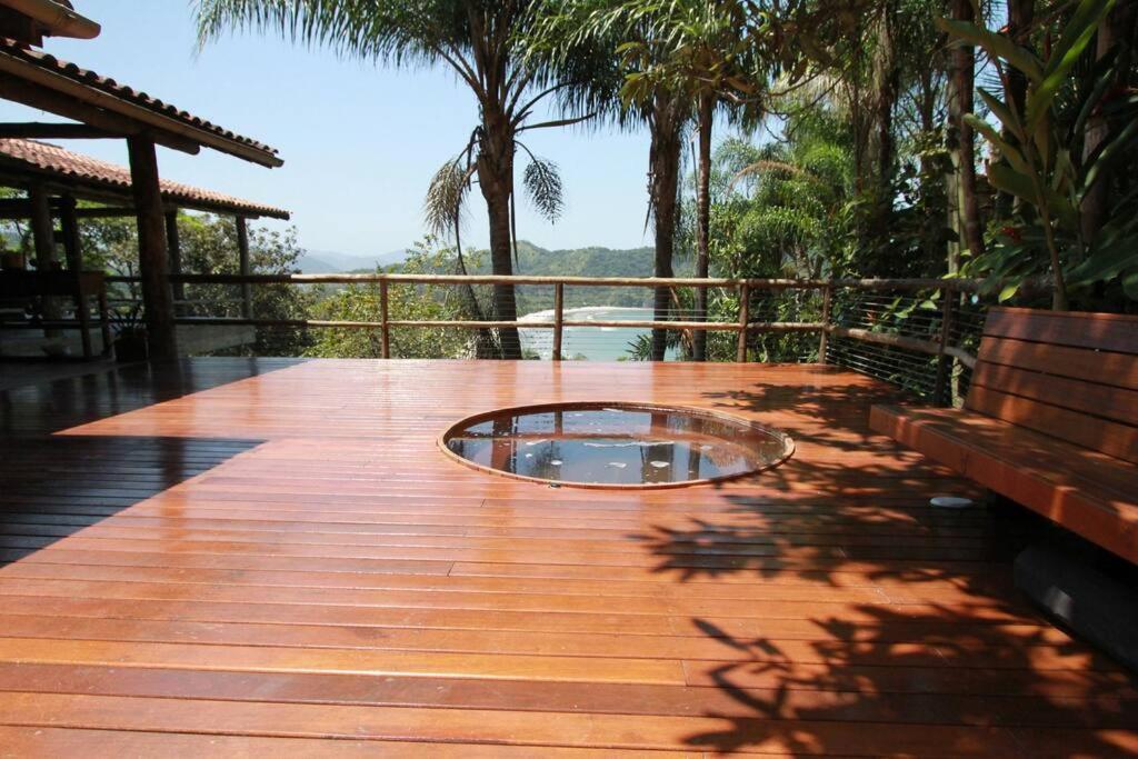 eine Holzterrasse mit einem Pool in der Mitte in der Unterkunft 5 suítes-Cond. fechado- Vista para a Barra do Sahy in São Sebastião