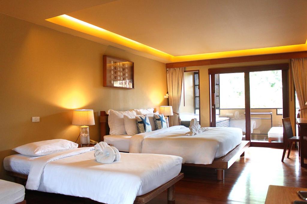 a hotel room with three beds and a window at Deva Beach Resort Samui in Choeng Mon Beach
