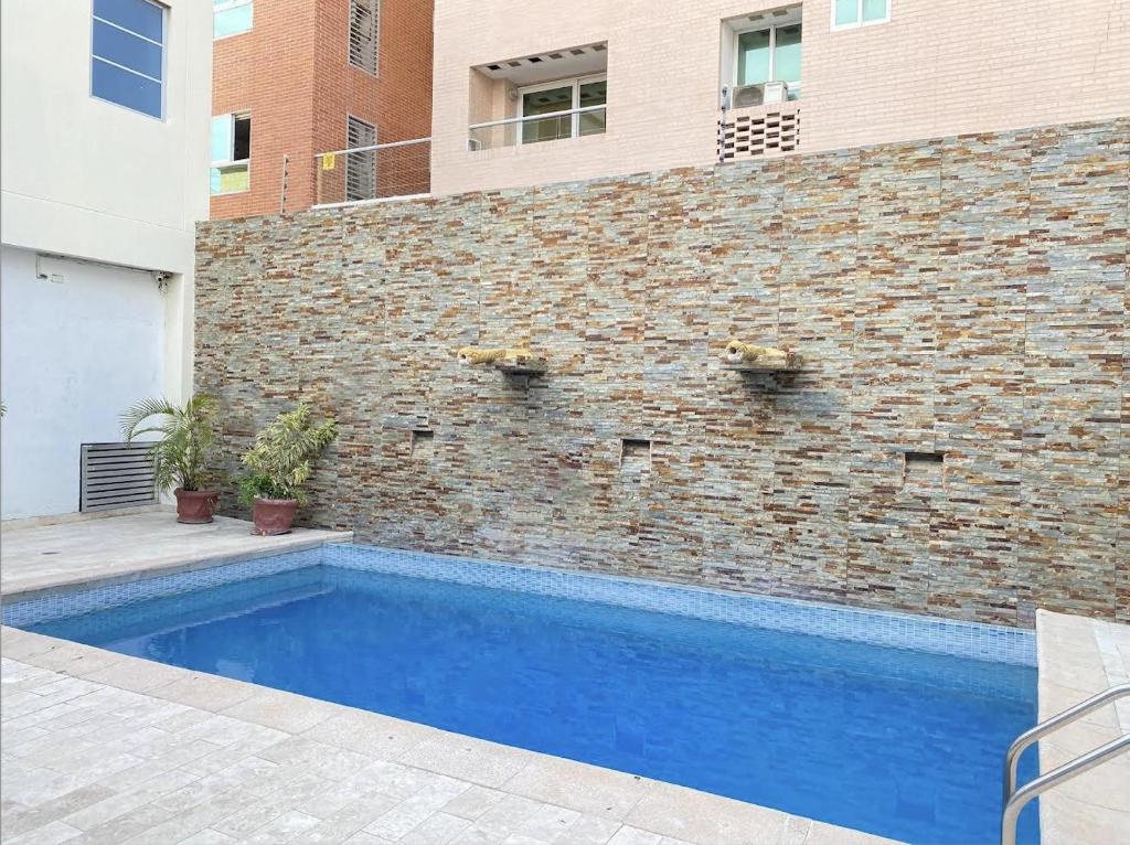 a swimming pool in front of a brick wall at Hotel Continental Plaza in Barranquilla