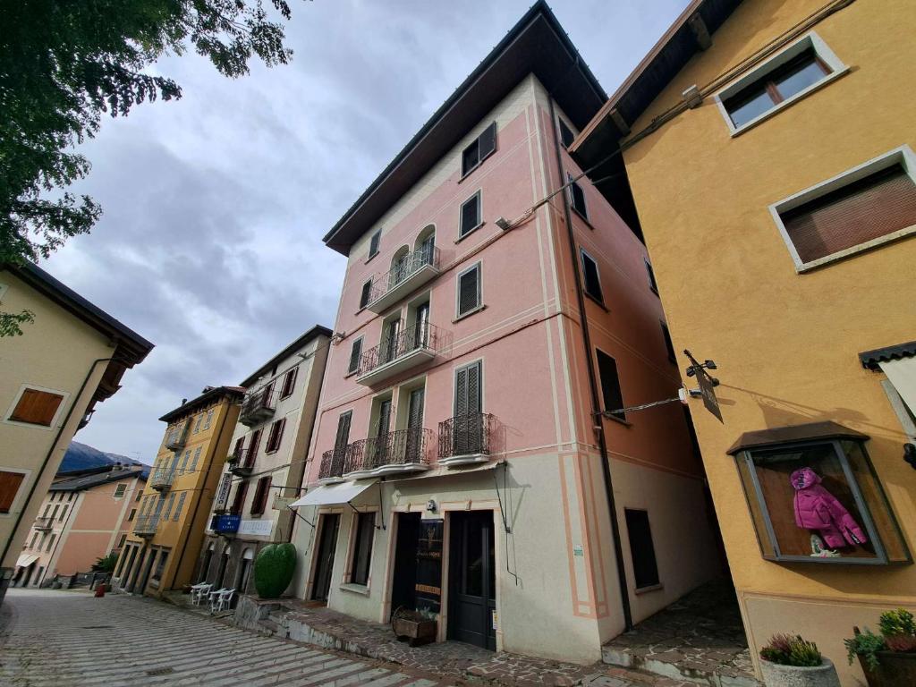 un edificio rosa sul lato di una strada di GRAYNITE-Old Village Apartment a Ponte di Legno