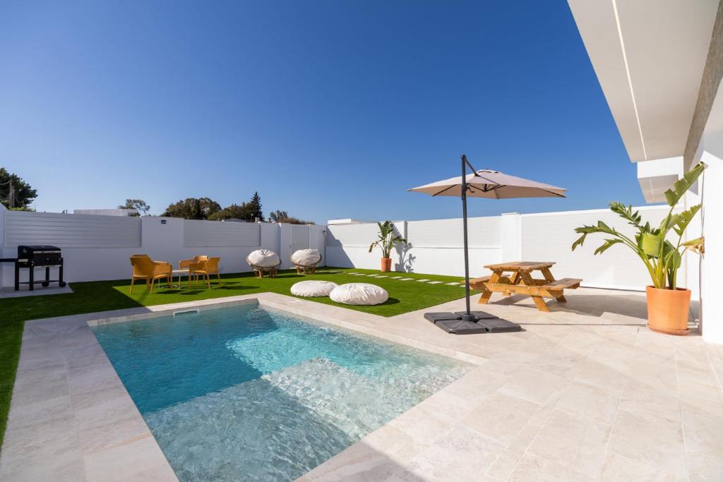 a backyard with a swimming pool and an umbrella at Villa Sanchez in Chiclana de la Frontera