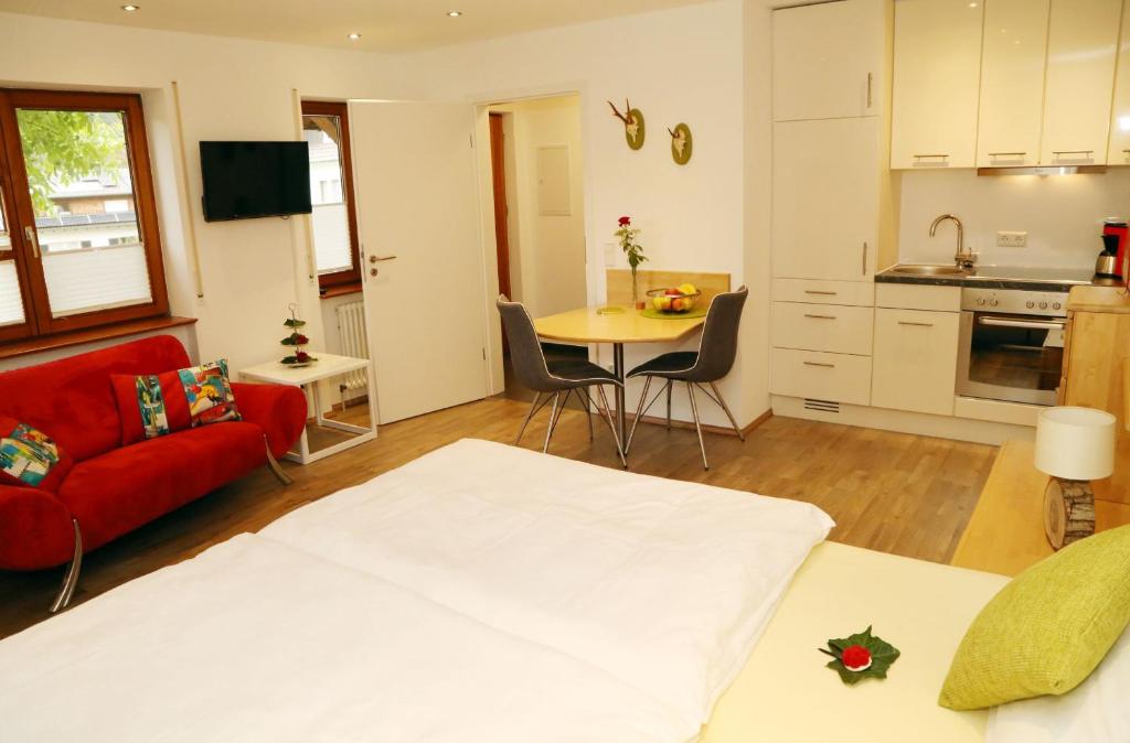 a living room with a red couch and a kitchen at Appartement Schwarzwaldstüble in Oberharmersbach