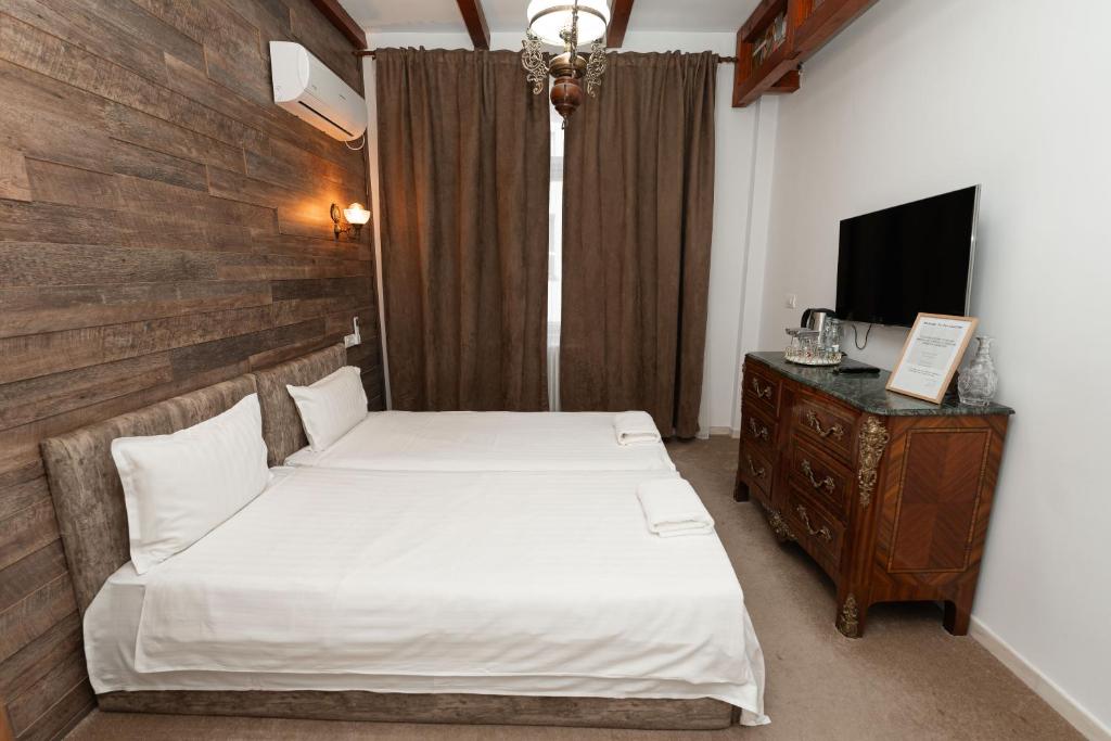 1 dormitorio con 1 cama, vestidor y TV en George&Dragon Rooms, en Bucarest