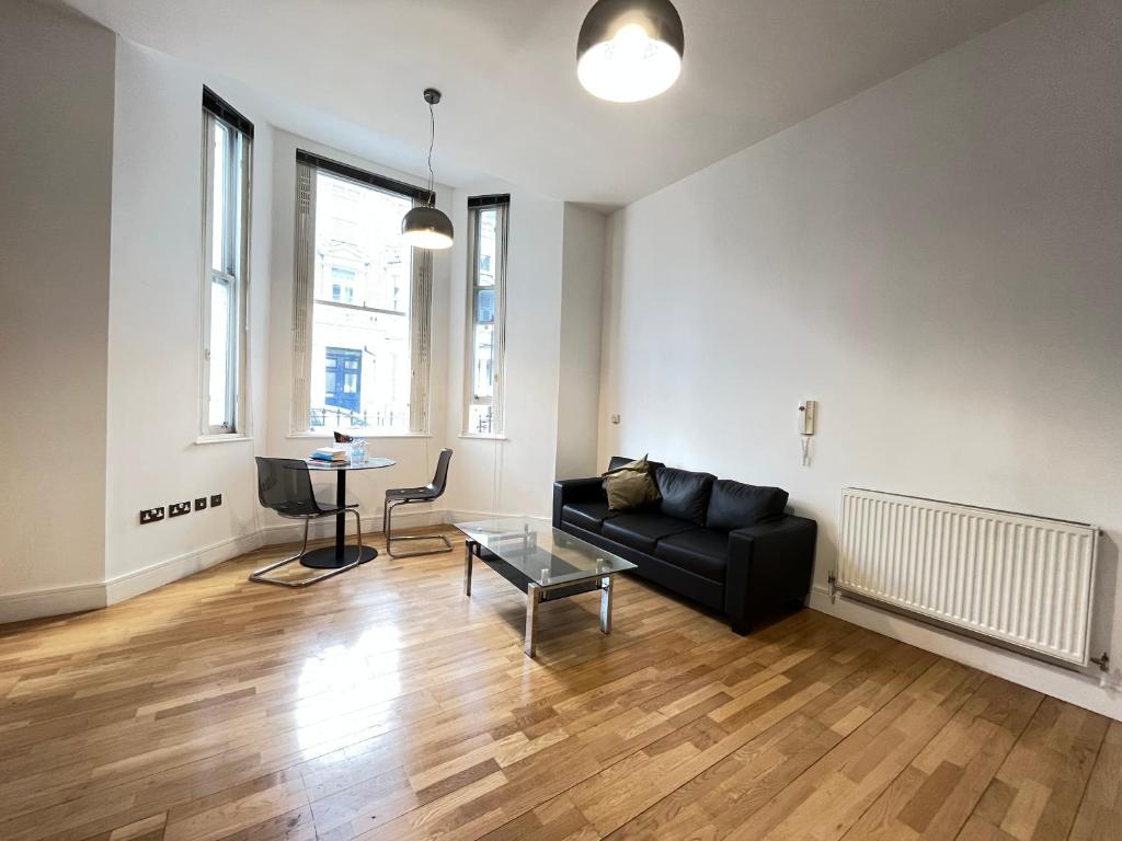 a living room with a black couch and a table at Serviced apartment in Kensington London Victoria in London