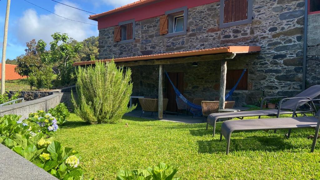 uma casa de pedra com um quintal com cadeiras em Madeira Bird House - House in the Mountains With Garden em São Vicente