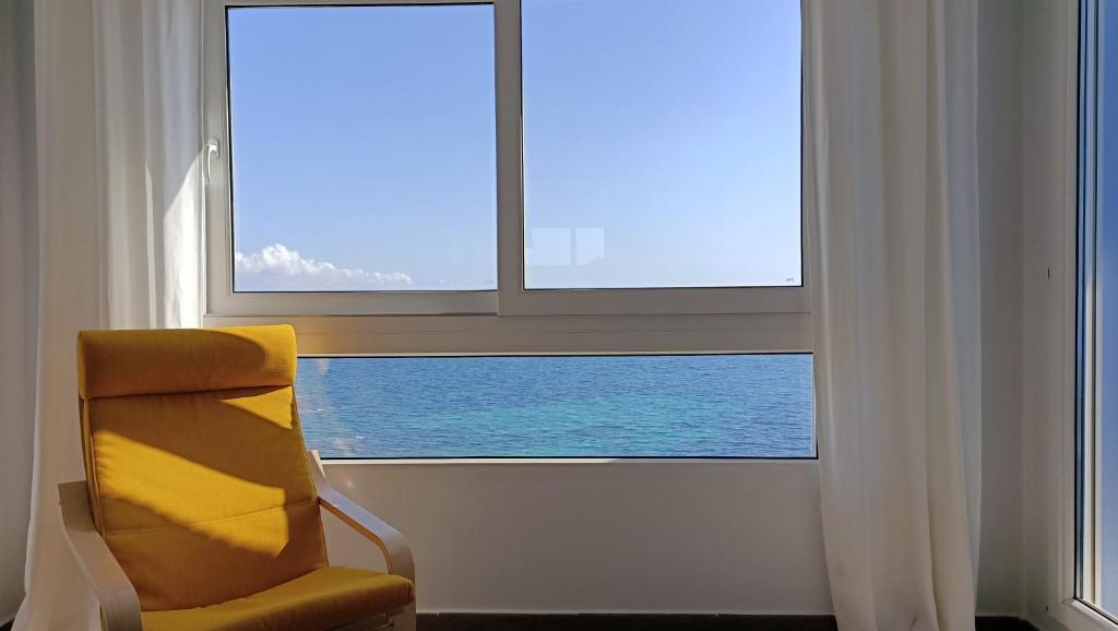 einem gelben Stuhl vor einem Fenster in der Unterkunft Junto Al Mar III in La Manga del Mar Menor