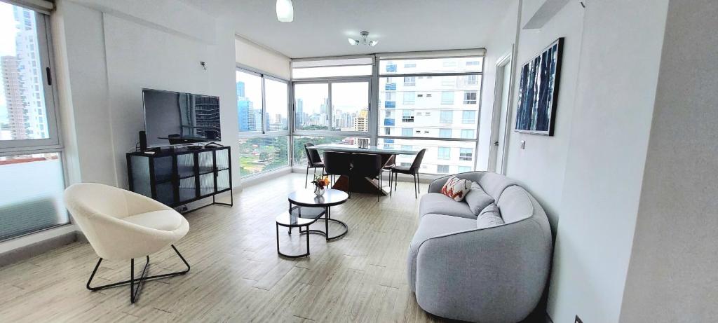 uma sala de estar com um sofá e cadeiras e uma televisão em Splendid Apartment City Center - PH Quartier Atlapa na Cidade do Panamá