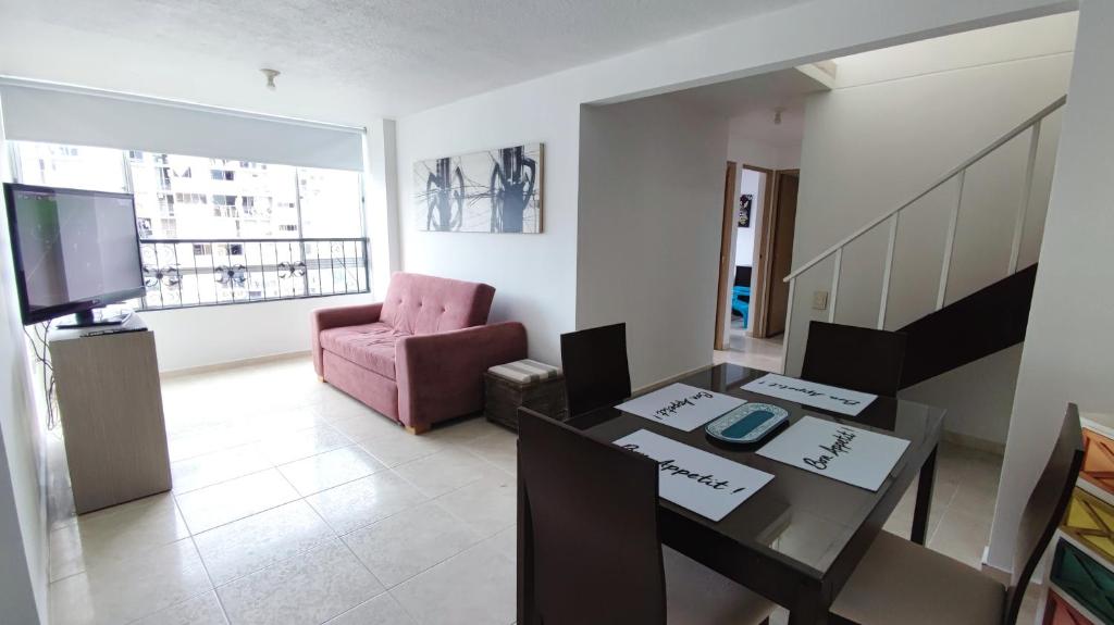 een woonkamer met een tafel en een roze stoel bij Apto y PH amplios, 3 a 4 alcobas, vista y turismo - Cacique in Bucaramanga