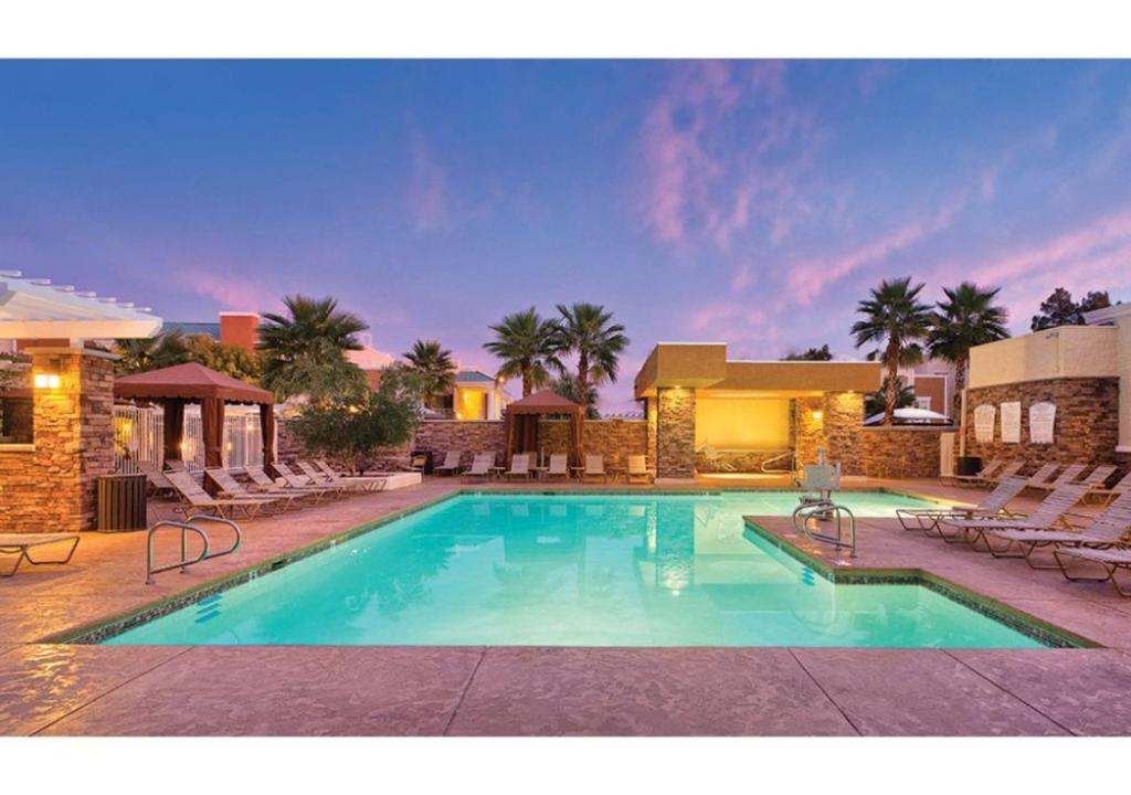 a large swimming pool with chairs and a building at Escape to Tropicana, a Tranquil Condo Oasis Near the LV Strip - Special Offer Now! in Las Vegas