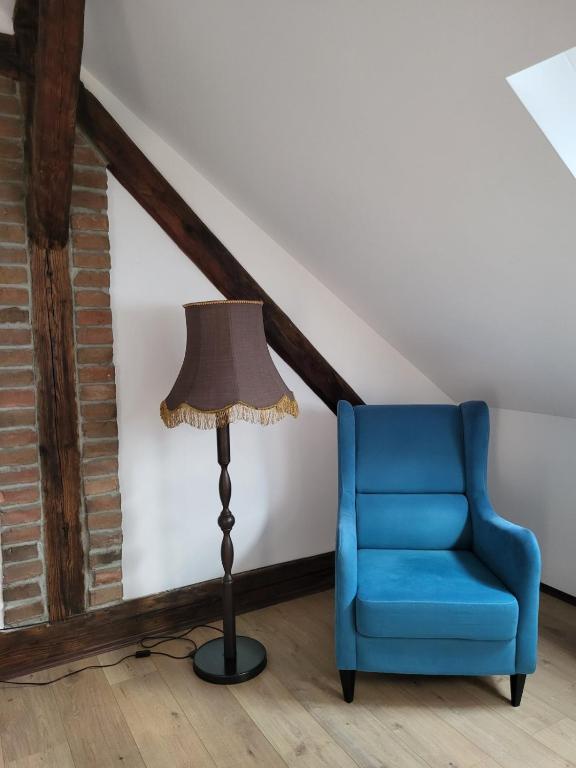 a floor lamp and a blue chair in a room at Apartment By the River in Niš