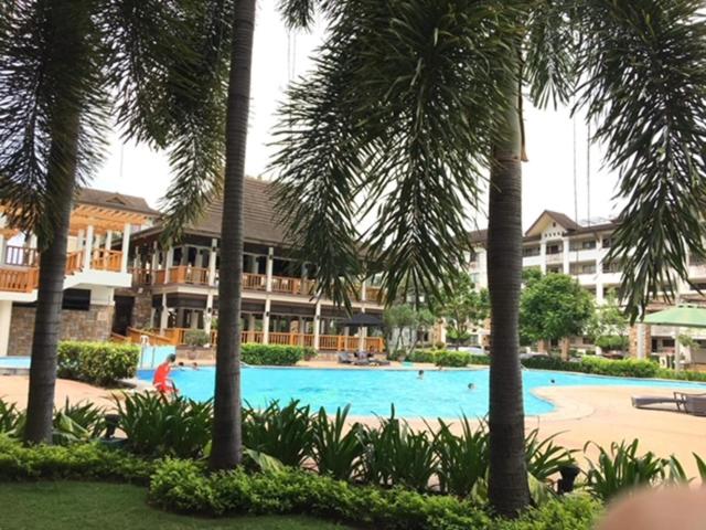 a swimming pool with palm trees in front of a hotel at Appartement: 2 BR at One Oasis in Davao City