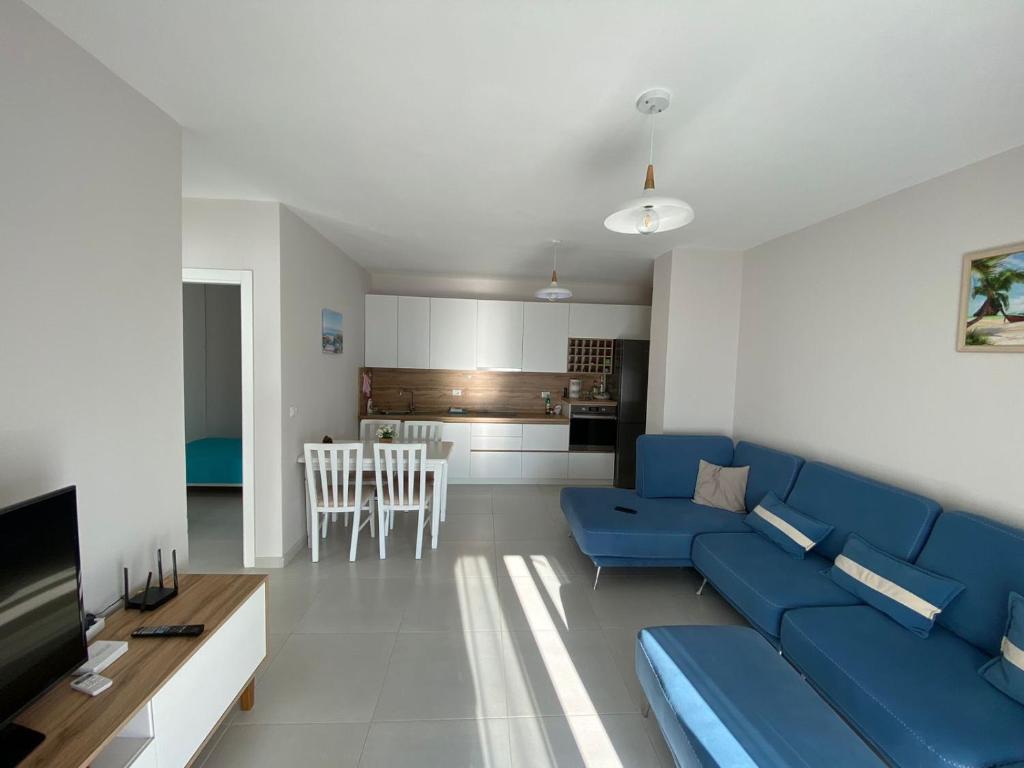 ein Wohnzimmer mit einem blauen Sofa und einer Küche in der Unterkunft Avenir Apartment in Durrës